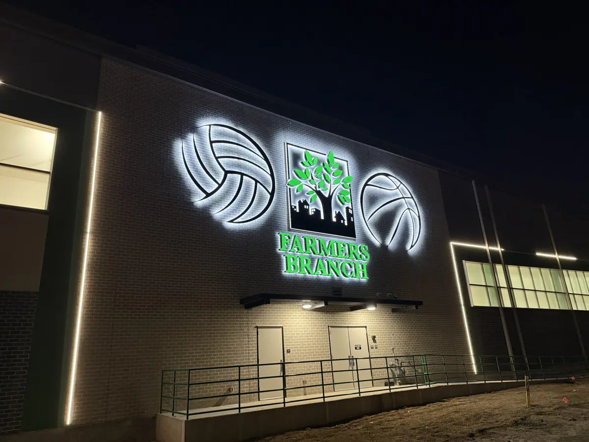 Backlit dimensional logo signs with halo effect glowing at night on Farmers Branch building in Dallas
