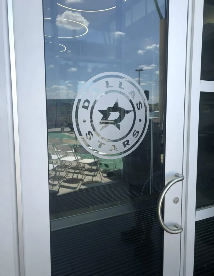 Frosted and cut vinyl window graphic of the Dallas Stars logo on a glass door