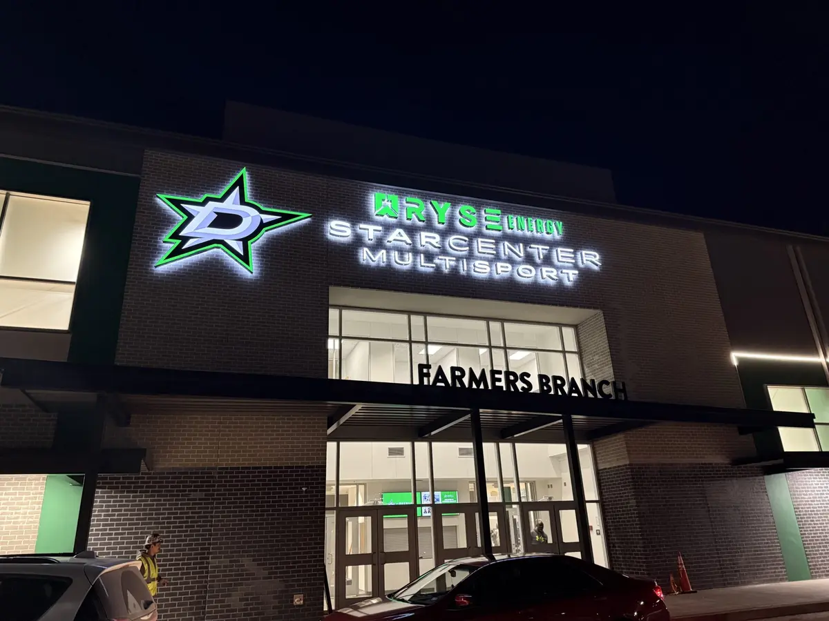 Halo-lit channel letter sign with Dallas Stars logo glowing at night on the StarCenter Multisport facade in Farmers Branch Dallas