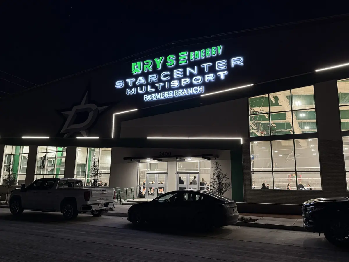 LED channel letters glowing at night on RYSE Energy StarCenter Multisport facade in Dallas