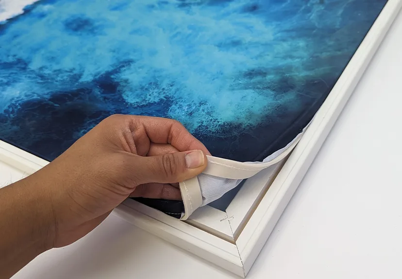 Close-up of a silicone edge graphic being tucked into an aluminum SEG frame groove