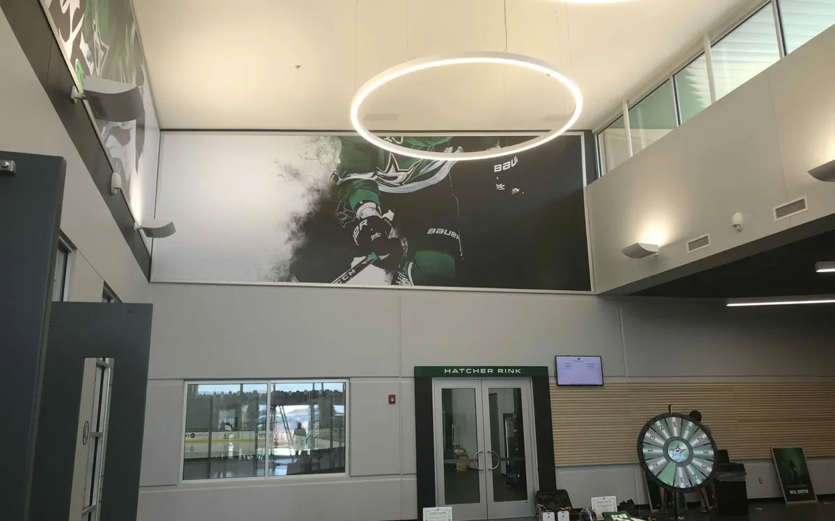 Large wall mural of a Dallas Stars player installed at the Hatcher Rink lobby
